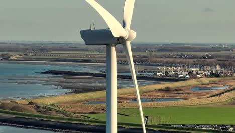 Aerial-closeup-shot-of-a-wind-turbine-in-a-rural-area-in-the-Netherlands-at-sunset-on-a-sunny-day