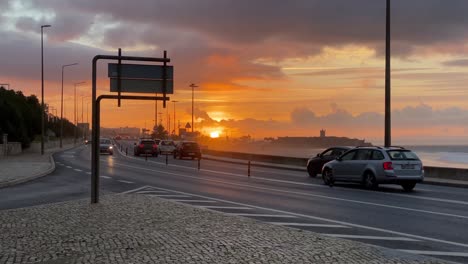 Schöner-Weitblick-Auf-Die-Autos,-Die-Bei-Majestätischem-Sonnenaufgang-In-Den-Straßen-In-Der-Nähe-Des-Carcavelos-strandes-In-Portugal-Fahren