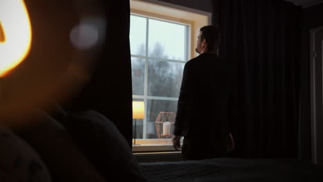 Man-facing-bedroom-window-showing-frustration