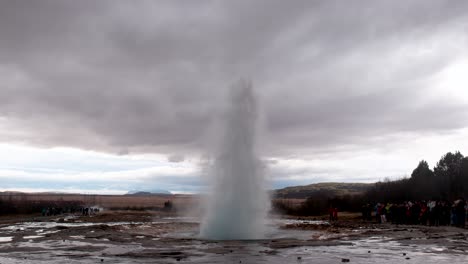 Tourists-At-The-Great-Geysir-Eruption-With-Gloomy-Sky-In-Southwestern-Iceland