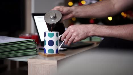 Caucasian-Man-Pouring-Coffee-Into-A-Mug-In-His-Home-Office-During-Christmas-Time,-4k