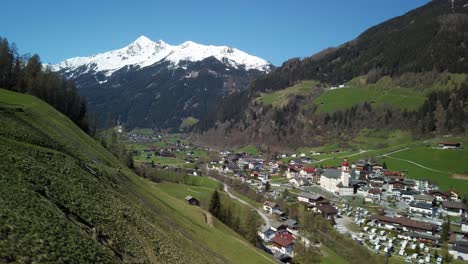 Uphill-camera-drive-above-Neustift-in-Stubai-Valley-in-Austria,-with-snow-covered-mountains-in-the-background