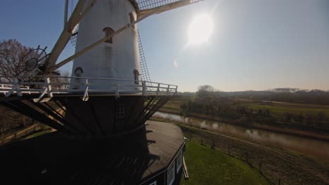 FPV-drone-shot-of-a-stationary-traditional-white-windmill-in-the-Netherlands-against-a-blue-sky
