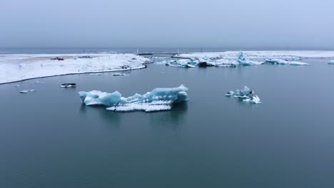 Vuelo-Aéreo-Hacia-Atrás-De-Icebergs-En-La-Laguna-Del-Río-Glacial-De-Jökulsarlon-Durante-El-Día-De-Niebla-En-Islandia