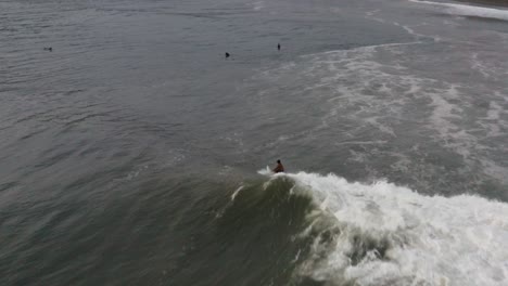 Aerial-follow-view:-Surfer-riding-wave-back-to-beach