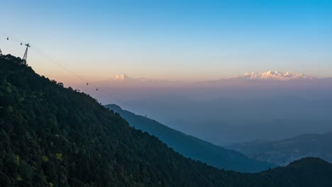 The-sun-setting-over-the-Himalayan-Mountains-and-a-cable-car-going-up-and-down-the-mountain-in-the-foreground