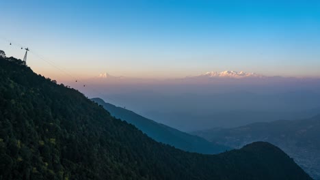 Die-Untergehende-Sonne-über-Den-Himalaya-bergen-Und-Einer-Seilbahn,-Die-Den-Berg-Im-Vordergrund-Auf-Und-Ab-Fährt