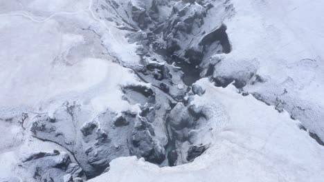 Icy-and-snow-covered-surface-of-Fjaðra-rglju-fur-Canyon-in-Iceland---aerial-shot