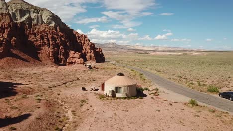 Drone-Aerial-View-of-Yurt-Tent-Under-Red-Rock-Sandstone-Formation-in-Goblin-Valley-State-Park,-Utah-USA