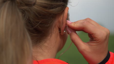 Close-up,-back-of-blonde-caucasian-runner-woman's-head-putting-on-earphones