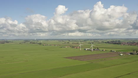 Aerial-shot-of-wind-turbines-on-lush-green-farmland-in-Friesland,-the-Netherlands,-on-a-beautiful-sunny-summer-day