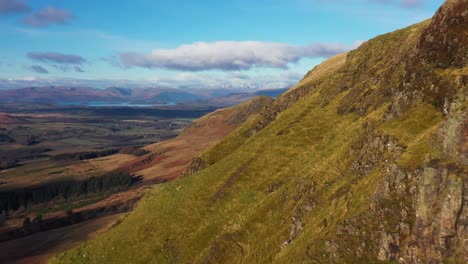 Cinematic-aerial-footage-of-close-fly-along-Campsie-Fells-cliffs-revealing-Dumgoyne-above-Glengoyne,-Stirlingshire