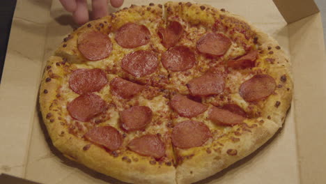 Hand-Greifendes-Stück-Peperoni-Pizza,-Das-Von-Der-Ganzen-Pizza-Gegriffen-Wird---Mittelgroß