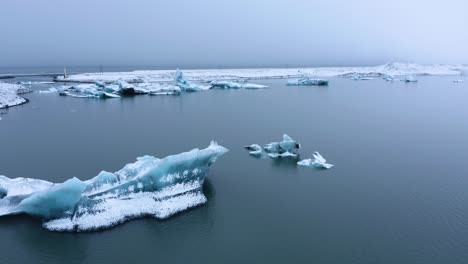 Aerial-panning-shot-of-glacial-lake-Jo-kulsa-rlo-n-with-Icebergs-during-cloudy-day-in-Iceland