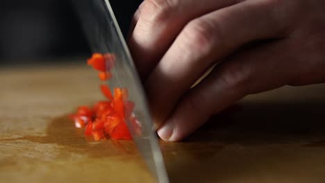 Male-hands-dicing-red-bell-pepper-with-sharp-knife-brunoise-style-on-wooden-chopping-board,-SLOW-MOTION