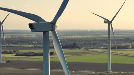 Aerial-closeup-shot-of-the-rotating-blades-on-wind-turbines-in-a-rural-area-at-sunset