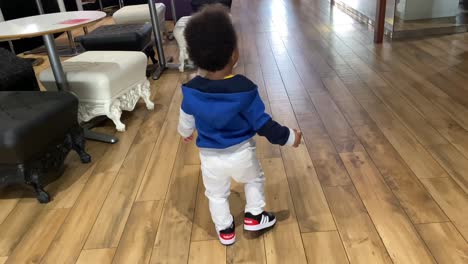 Afro-european-boy-of-1-and-a-half-year-walking-wearing-blue-shirt-and-white-jeans-from-the-back