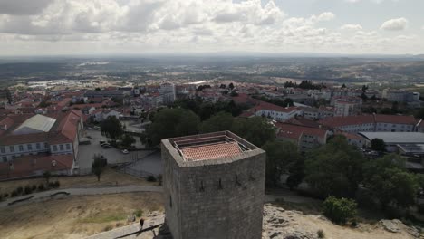 drone-flight-over-the-Tower-of-Castelo-da-Guarda,-Guarda-Castle,-in-Portugal,-with-rooftops-and-cityscape-in-background