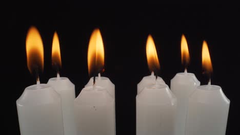 Makroansicht-Brennende-Weiße-Kerzen-Auf-Schwarzem-Hintergrund,-Stille-Nacht,-Denkmal,-4k-Statische-Aufnahme