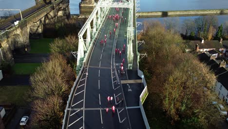 Charity-Santa-dash-fun-run-over-Runcorn-Silver-Jubilee-bridge-Aerial-view-rising-tilt-down-shot