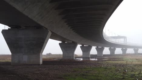 Ghostly-misty-concrete-support-structure-under-motorway-flyover-panning-right