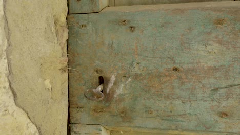 Close-up-shot-of-an-old-wooden-door-with-a-rusty-key-in-the-keyhole