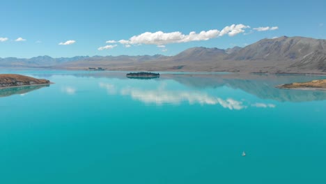 Aerial-view-of-Lake-Tekapo,-New-Zealand,-with-a-camera-pan-over-the-lake-during-a-sunny-day