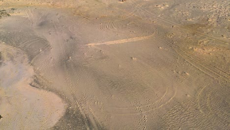 Forward-moving-drone-over-vast-barren-sandy-land-on-bright-sunny-day