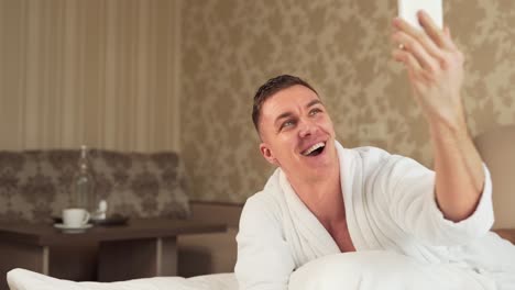 handsome-sporty-guy-in-robe-takes-selfie-on-phone