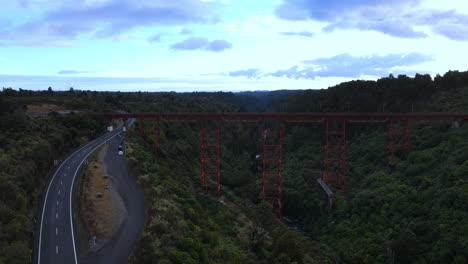 Tiro-De-Retroceso-De-Drones-Del-Puente-Ferroviario-Rojo-Sobre-George-Con-árboles-Y-Río-Y-Carretera