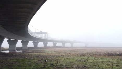 Ghostly-misty-concrete-support-structure-under-motorway-flyover-slow-left-pan
