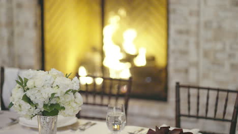 Wedding-dining-table-prepared-for-guests-by-cozy-fireplace
