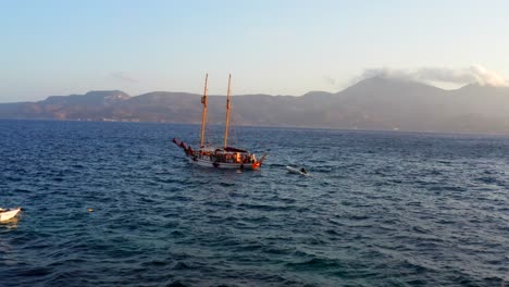 Wooden-ship-tour-in-the-greek-Mediterranean-sea-around-milos-island,-drone-scene