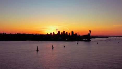 Wide-aerial-golden-sunset-cityscape-of-Auckland-city-and-sailboat-regatta