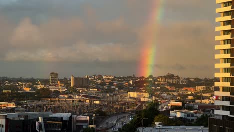 Sky-clear-up-after-a-heavy-rainfall-in-the-afternoon,-beautiful-rainbow-with-golden-sun-shinning-across-mayne-railway-yard-in-Bowen-Hills-and-Windsor-inner-city-suburb-of-Brisbane,-Queensland