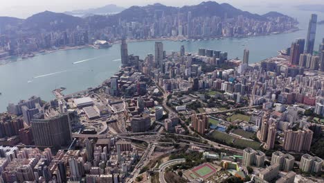 Hong-Kong-skyline,-Slow-aerial-pass-heading-towards-Victoria-Harbour,-above-Kowloon-bay-and-urban-area