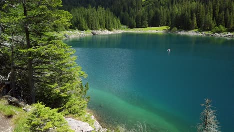 Beach-with-trees-and-blue-colored-water-of-the-Obernberger-Lake-in-Tyrol,-Austria