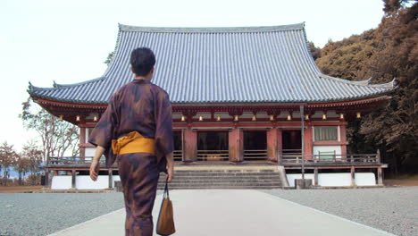 Guy-wearing-a-Yukata-walking-towards-a-temple-to-go-pray-in-Kyoto,-Japan-soft-lighting