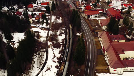 Aerial-Drone-Shot-of-Romanian-Trains-in-Predeal-Village,-Romania-in-The-Snow-During-Winter