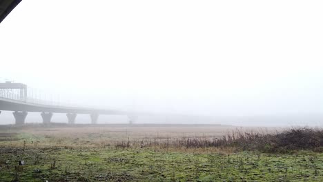 Ghostly-misty-concrete-support-structure-under-motorway-flyover-slowly-panning-left