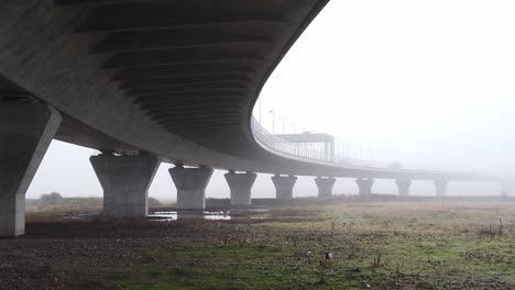 Ghostly-misty-concrete-support-structure-under-motorway-flyover-pan-left