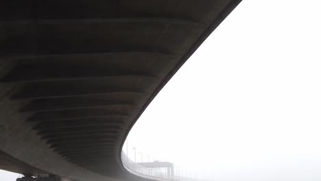 Below-large-curved-concrete-motorway-infrastructure-tilting-down-to-misty-sinister-overpass-landscape