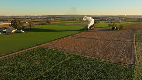 Drone-View-of-a-Steam-Engine-Approaching-Blowing-Lots-of-Smoke-in-the-Early-Morning-Traveling-Thru-the-Farmlands-on-Fall-Morning