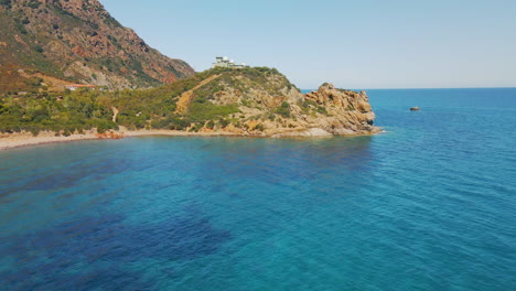 Gorgeous-Mountain-Promontory-Overlooking-The-Calm-Blue-Sea-Of-Sardinia-During-Summer-In-Italy---Aerial-drone-wide-shot-in-slow-motion