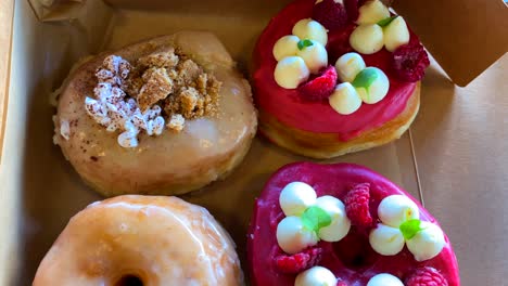 Delicious-mix-of-sweet-doughnuts-with-raspberry-glaze,-cookies-and-cream,-fresh-raspberries,-deep-fried-tasty-donut-snacks,-4K-shot