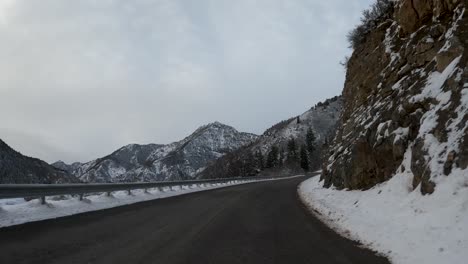 Winter-POV-Shot-Of-Car-Driving-Snowy-Rocky-Mountain-Road