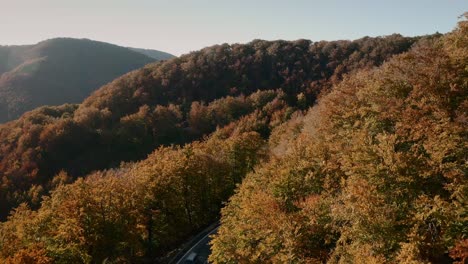 Aerial-reveal-footage-of-cars-driving-on-a-scenic-road-in-an-autumn-coloured-forest-in-a-picturesque-Slovak-countryside