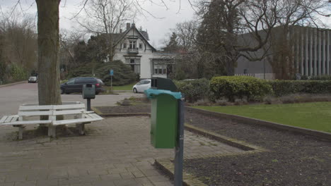 Garbage-bin-in-small-park-with-trash-bag-in-the-wind