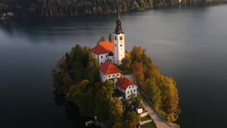 Revealing-drone-shot-of-the-Pilgrimage-Church-of-the-Assumption-of-Mary,-Slovenia-during-the-golden-hour