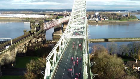 Charity-Santa-dash-fun-run-over-Runcorn-Silver-Jubilee-bridge-Aerial-view-descending-pull-back